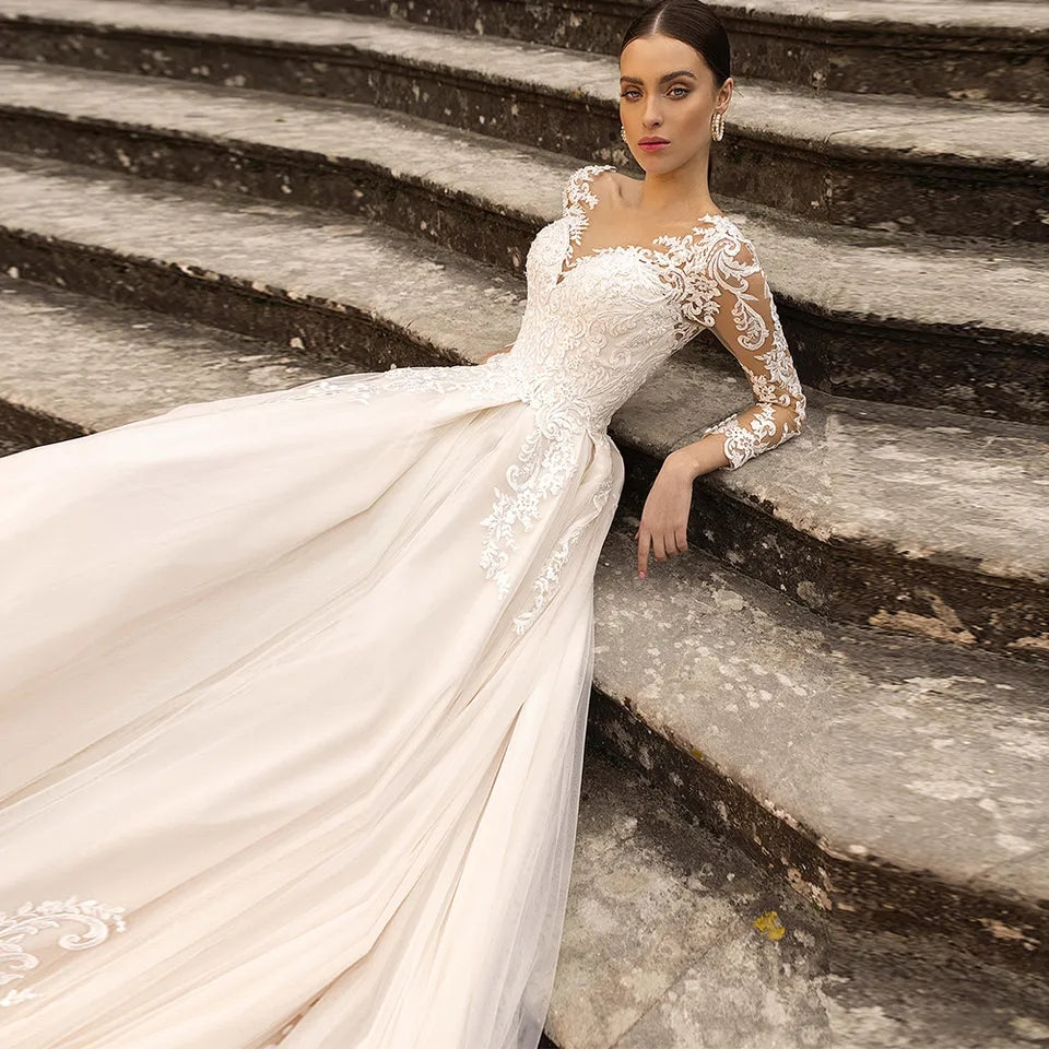 Abito da sposa di lusso con maniche lunghe in pizzo, applicazioni in tulle trasparente, schiena scoperta e gonna a-linea - Bridetobe.it