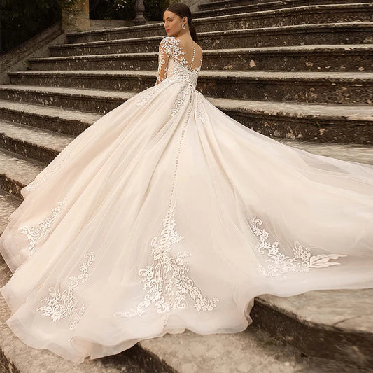 Abito da sposa di lusso con maniche lunghe in pizzo, applicazioni in tulle trasparente, schiena scoperta e gonna a-linea - Bridetobe.it